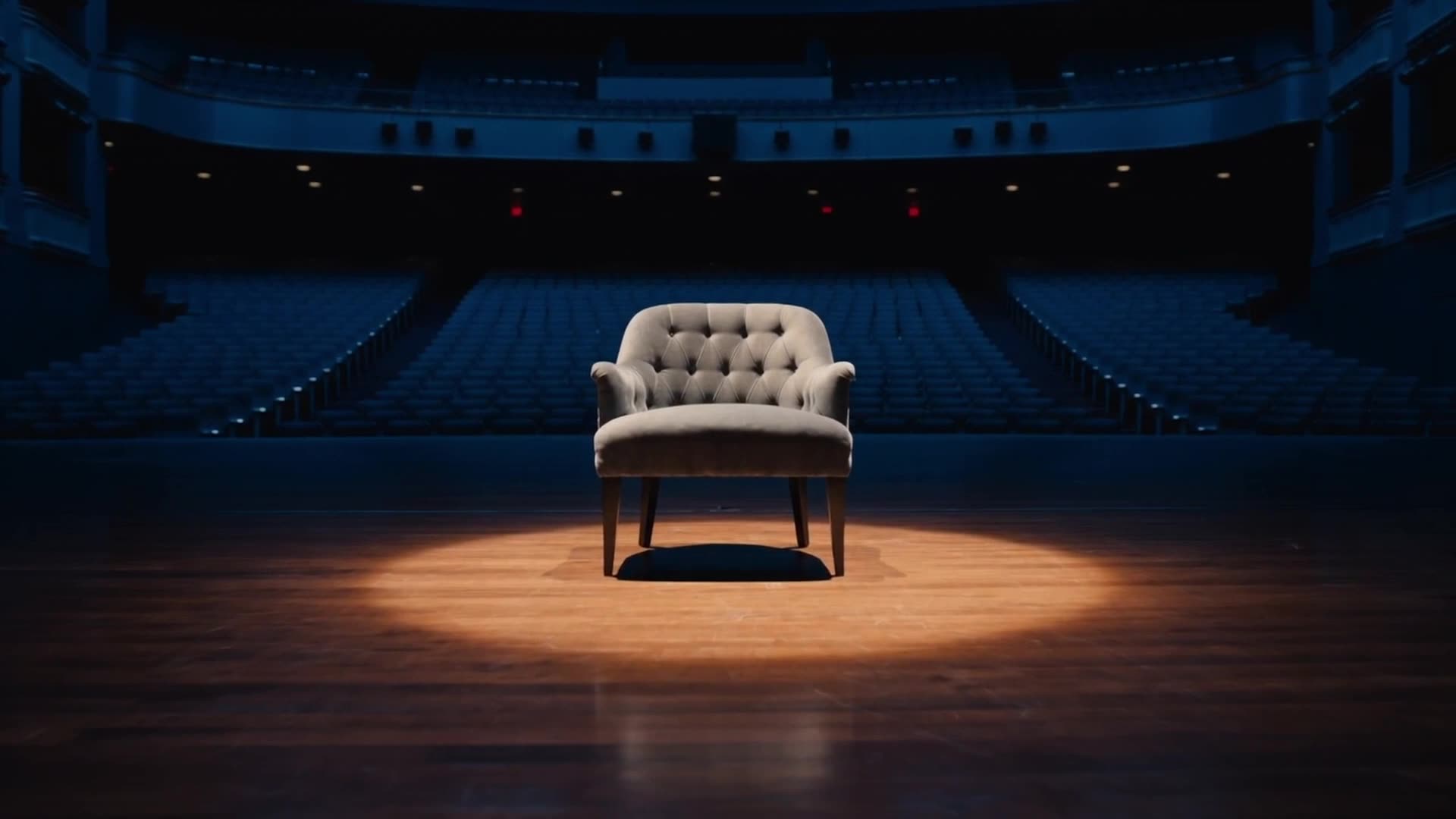 An empty armchair in a pool of light on the stage of the Atterbury Theatre