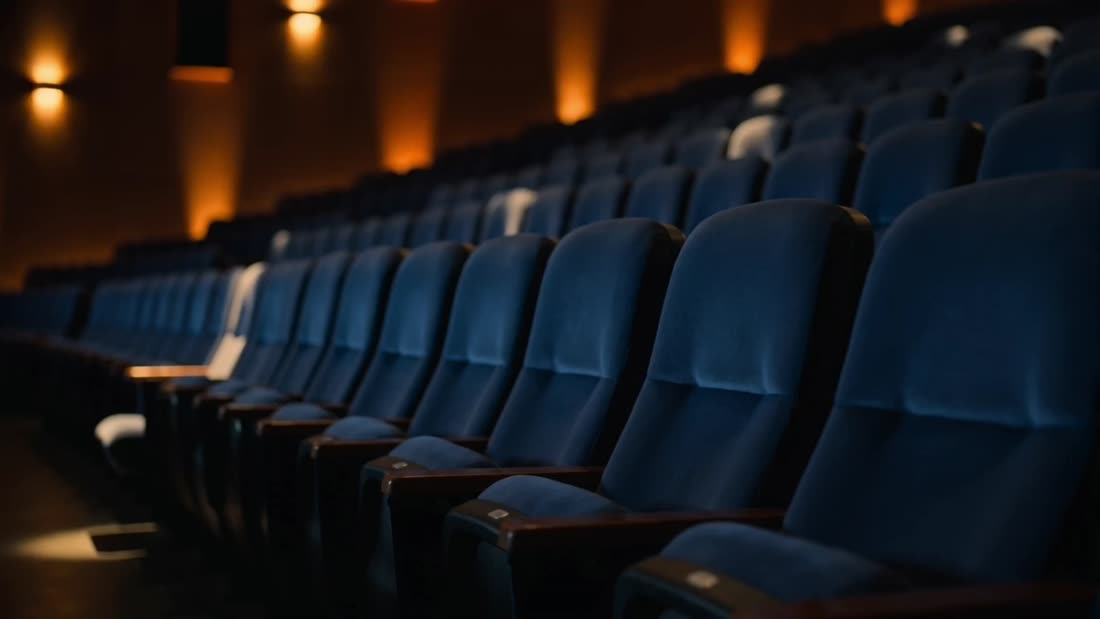 Rows of blue velvet seats in the auditorium, lit by warm wall lights